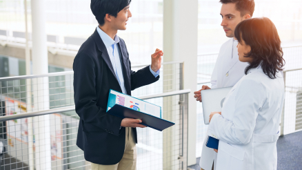 A sales rep engages with HCPs in lab coats.